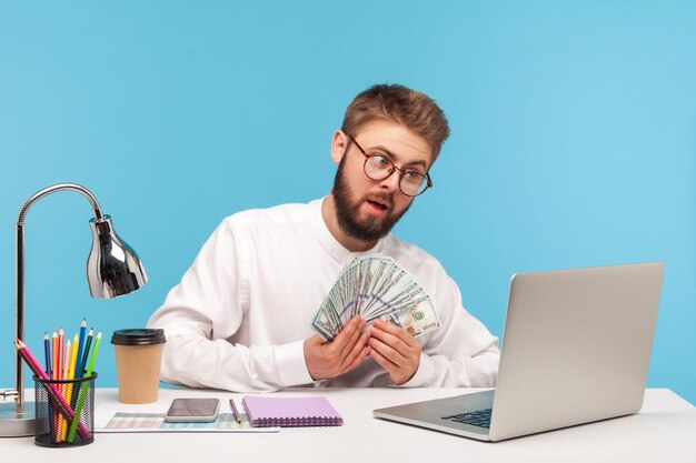 Photo self confident bearded man boss showing lot of dollar cash on laptop web camera