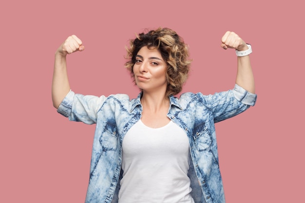 Photo self confident strong woman standing with raised arms showing her power looking at camera