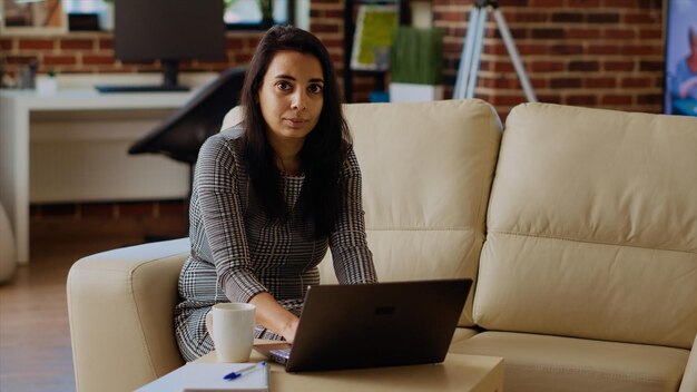 自営業の女性が自宅でラップトップのキーボードでタイピングしています