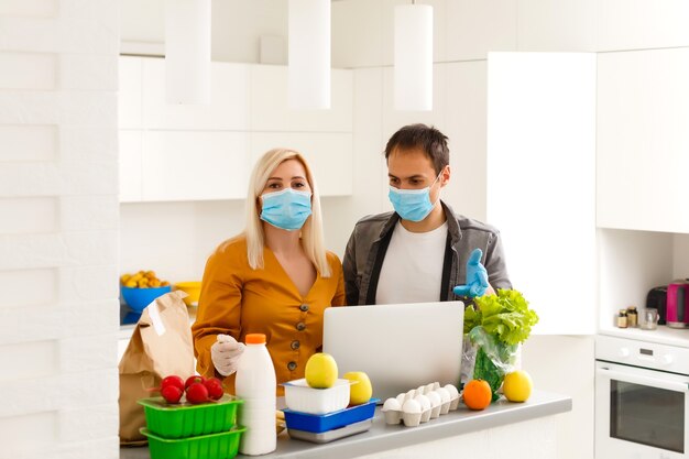 Self Isolation Concept. couple unpacking paper bag with food in kitchen, ready for quarantine during epidemic outbreak