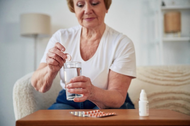 Photo self medicate taking medicine senior elderly woman is at home in the living room