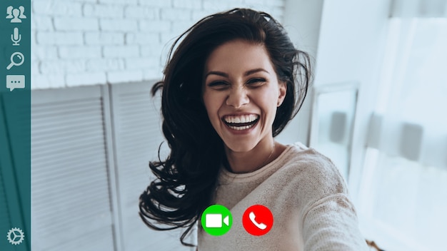 self portrait of attractive young woman smiling and looking at camera while having video call