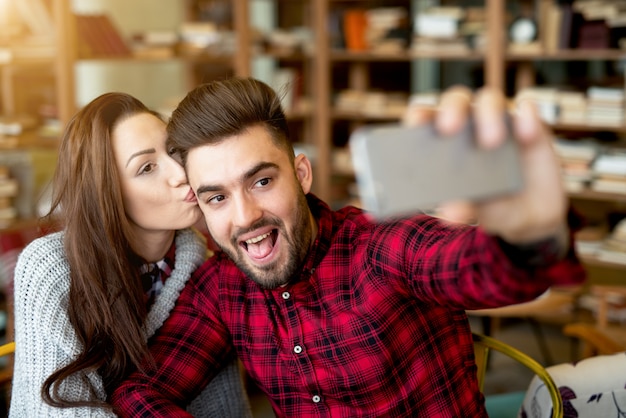 Autoritratto che fa alle coppie del ristorante che godono insieme. foto mobile in posa per i social network.