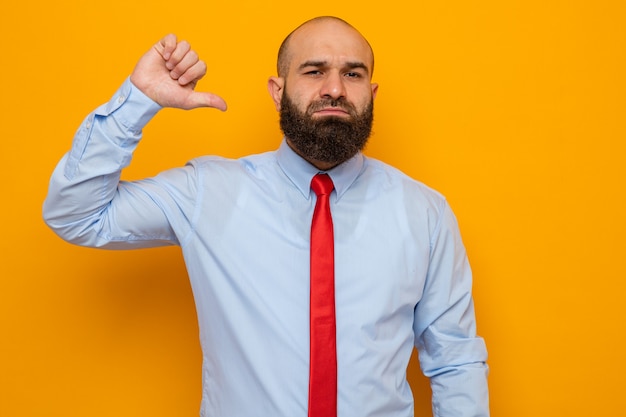 Self-satisfied bearded man in red tie and shirt looking pointing at himself