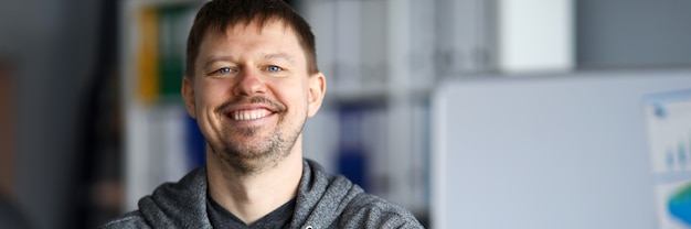 Self-satisfied man is standing in room and smiling