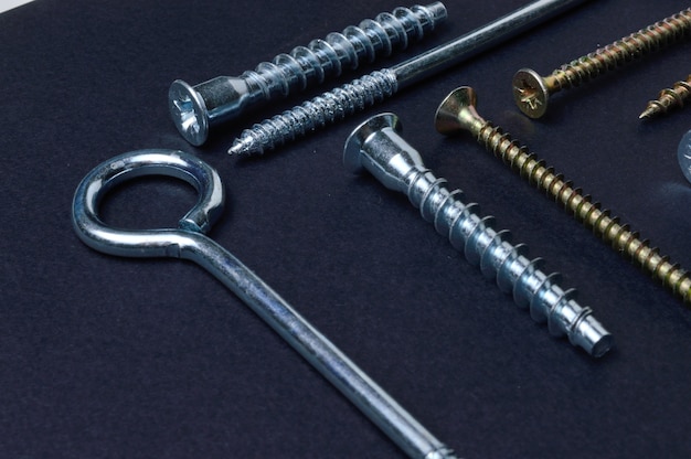 Self-tapping screws and various fittings are laid out on a dark background. close-up.