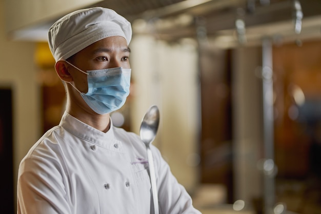 Foto giovane chef sicuro di sé in posa con maschera facciale