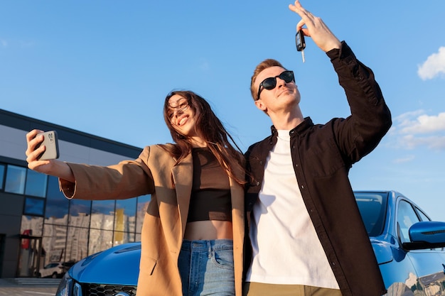 Selfie on the background of a new car A young couple bought a family car