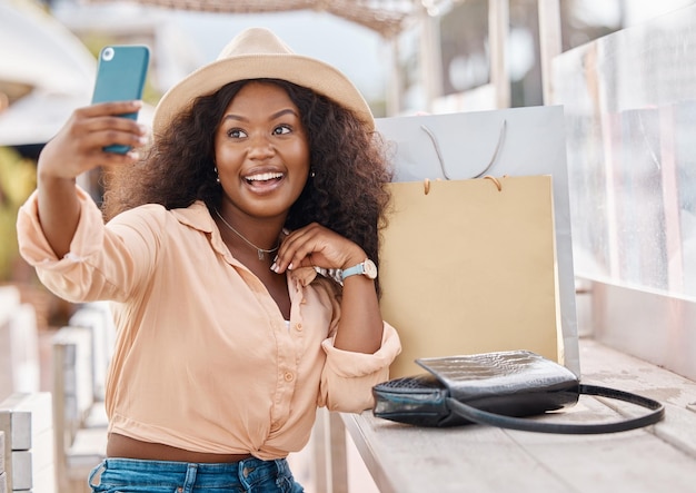 Selfie-boodschappentassen en vrouw met telefoon blij in hoed in stadscafé In het winkelcentrum meisje met glimlach en smartphone op 5g-videogesprek na kortingsuitverkoop bij luxe modewinkel op zomervakantie