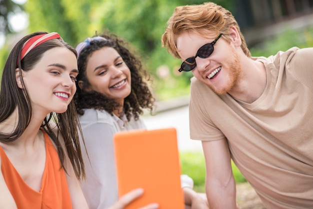 selfie. Drie jonge vrolijke vrienden in vrijetijdskleding die selfie op tablet buiten nemen op zomerdag