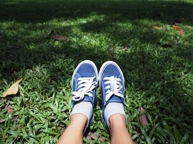 Selfie feet wearing blue sneaker on green grass in the park. 