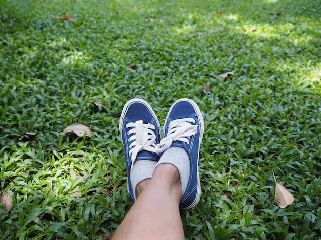 Selfie足は公園の緑の芝生に青いスニーカーを着ています。