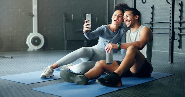 Selfie fitness and couple training with a phone happy with workout and smile for exercise at the gym Wellness photo and man and woman with love for sports and live streaming on social media