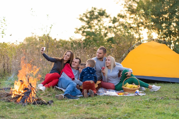 Selfie of friends on nature. Friends are resting near the lake. Great fun company. Big family gathered together on vacation. Children and parents on a picnic in the summer forest.