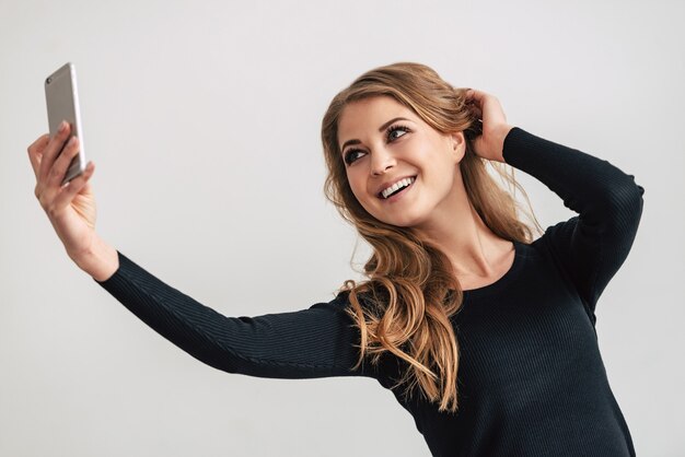 Selfie from beaut. Beautiful young woman making selfie while standing against white background