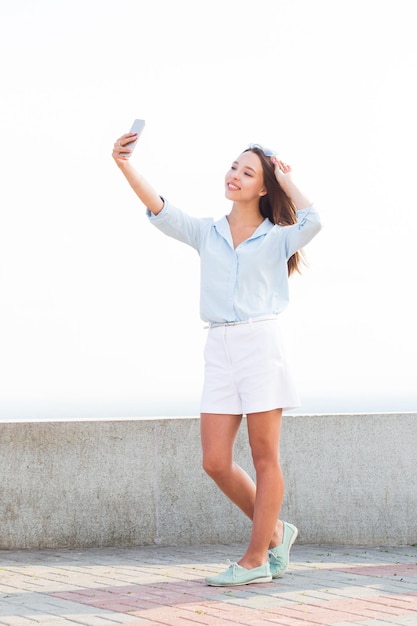 公園、屋外、通りのスマートフォンで自分撮りの女の子