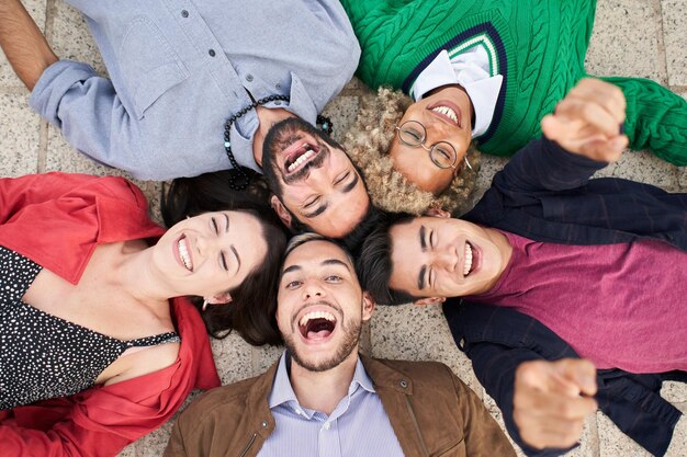 Selfie di un gruppo di amici sdraiati in cerchio guardando la telecamera