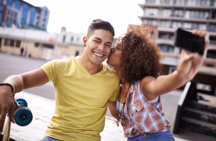 Photo selfie kiss and couple with skateboard in city for exercise training and sports hobby in town skate park fashion and man and woman on smartphone for social media networking and online picture