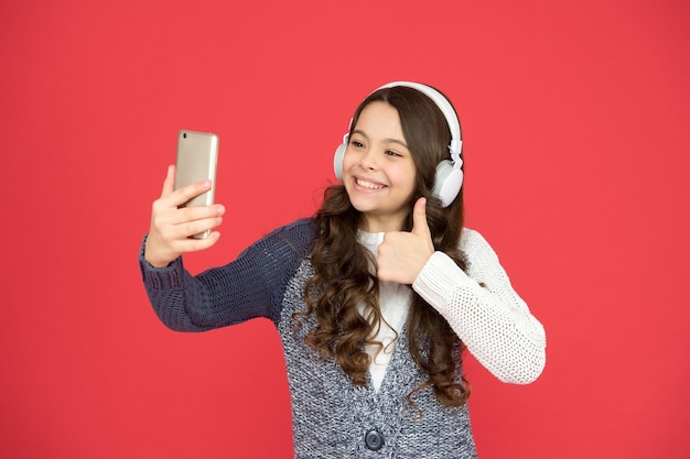 Selfie leuke tijd Mijn afspeellijst is de beste kleine meid bloggen modern leven concept kindergeluk van een kind Klein kind kiest muziek op smartphone Klein kind draagt een koptelefoon die muziek speelt