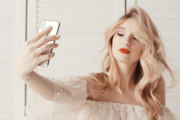 макияж для селфи блондинка / модель макияжа делает селфи на телефоне, концептуальный стиль, гламурная мода, макияж