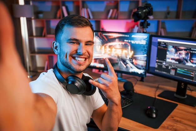 Foto selfie maken om de overwinning te vieren mannelijke game-streamer in vrijetijdskleding is binnenshuis met pc