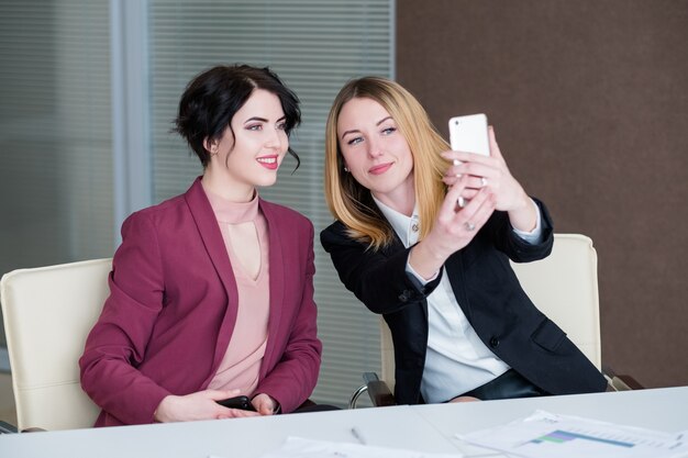 Selfie op het werk. zakenvrouwen vermaken zich tijdens de kantoorvergadering met het maken van foto's van zichzelf.