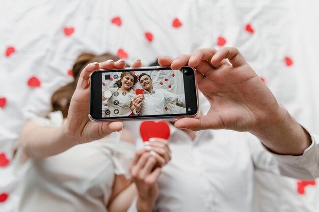 Foto selfie sullo schermo del telefono di uomo e donna innamorata nel letto