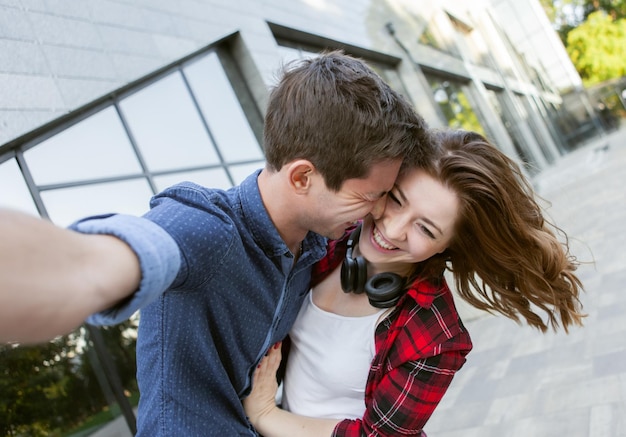 Selfie portrait of a cheerful funny couple in love. A couple is fooling around outdoors. Love concept