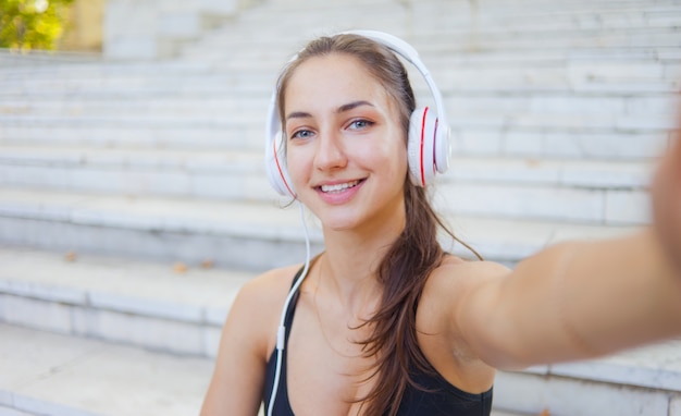 Selfie portrait of a cheerful sport woman in headphones. Healthy lifestyle.