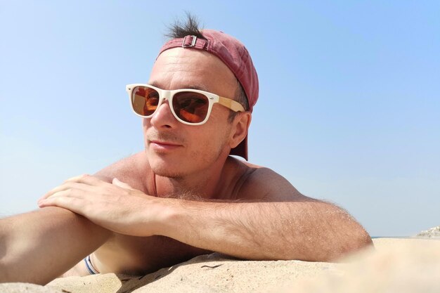 Photo selfie portrait of a man in sunglasses and a cap on the beach in summer summer holidays