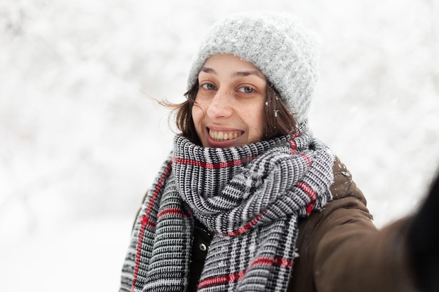 雪に覆われた冬の天候で若い陽気な女性の Selfie の肖像画