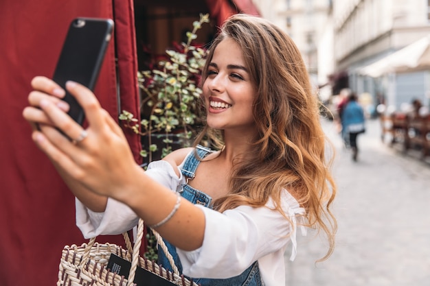 スマートフォンが付いている通りの若い女性のSelfieの肖像画