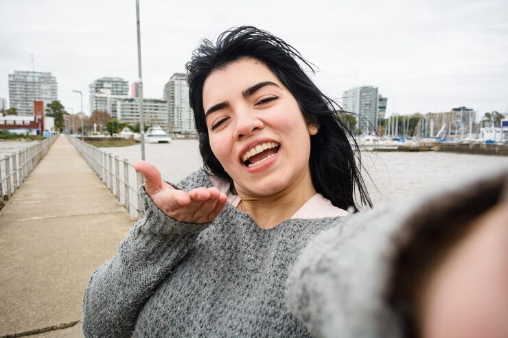 Selfie portret van jonge Latijnse vrouw die glimlacht en gelukkig naar de camera kijkt op de pier over de rivier