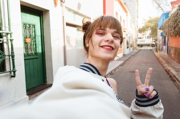 Selfie portret van jonge transgender vrouw die lacht maken v-teken met vingers telefoon perspectief