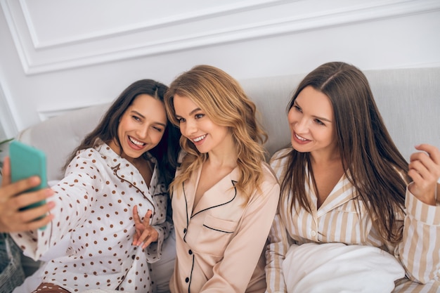 Selfie. three girls lying on bed and making selfie