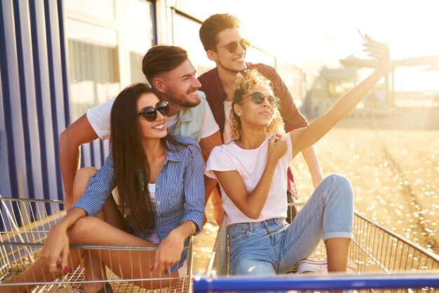 Selfie-tijd Twee mooie meisjes die plezier hebben op winkelwagentjes Jongeren racen op winkelwagentje