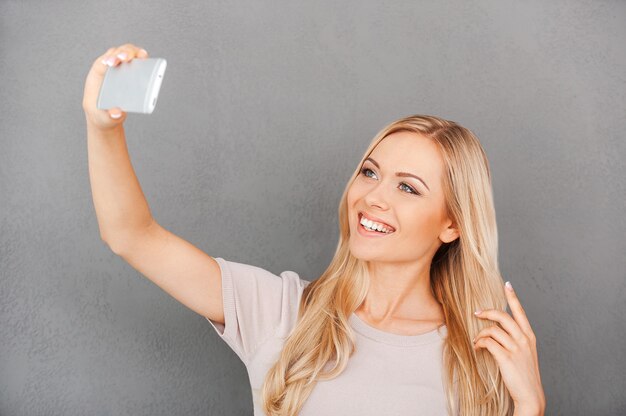 Selfie time! Cheerful young woman making selfie on her smart phone