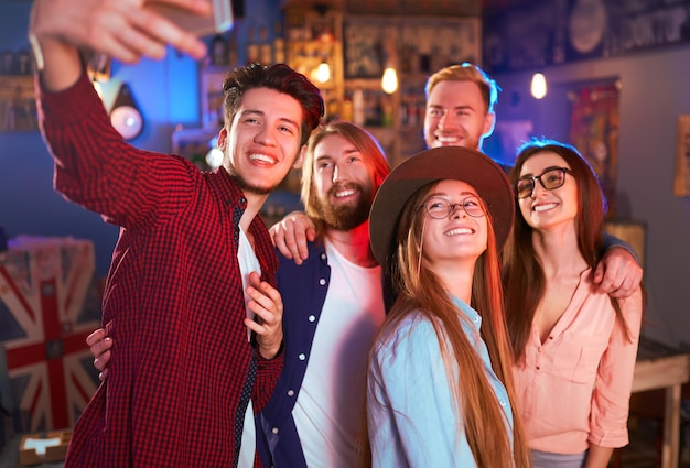 Selfie time young group of friends partying in a nightclub and\
toasting drinks happy young people