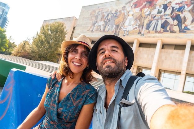 Selfie of a tourist couple visiting the national historical museum in skanderbeg square in tirana albania