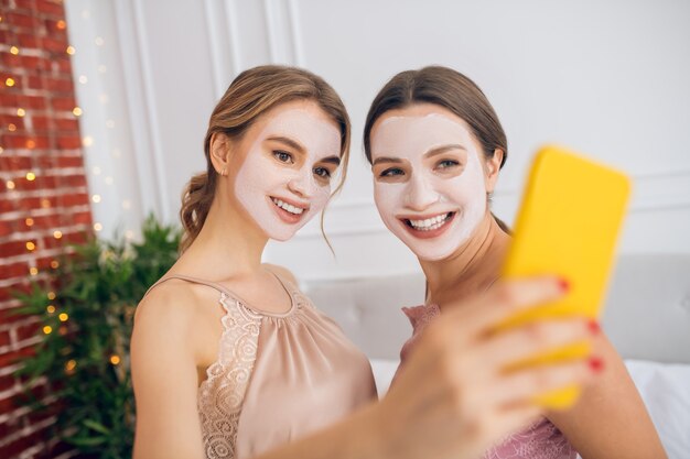 Autoscatto. due ragazze carine con maschere facciali che fanno selfie