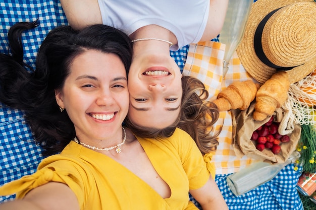 Selfie of two friends lying on blue blanket at picnic