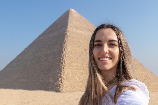 Selfie-weergave van mooie jonge vrouw met de grote piramide van Gizeh op de achtergrond zonder mensen