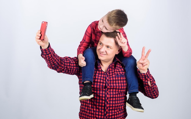Selfie with daddy fathers day Enjoying time together father and son in red checkered shirt Happy family together small boy with dad man childhood parenting selfie time lets make selfie
