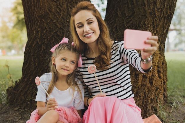 Foto selfie con la figlia. madre amorevole moderna che fa selfie memorabile con figlia carina e divertente