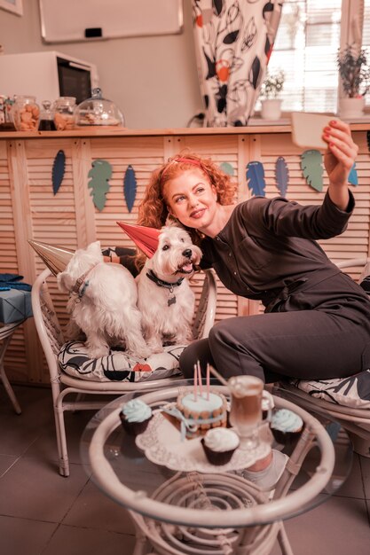 Foto selfie con i cani. una donna dai capelli rossi raggiante che ama i cani che si fa un selfie con i suoi cuties