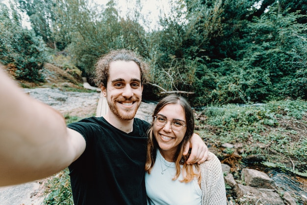 A selfie of a young couple giving a bis smile to the camera on the forest