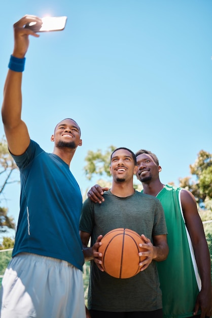 Selfiebasketbal en team met telefoon op de baan bij speltraining of -oefening Fitnesssporten en Afrikaanse atleten die na de wedstrijd foto's maken voor sociale media op het basketbalveld met mockup-ruimte