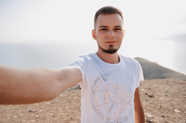 Selfieportrait di un giovane turista maschio sullo sfondo delle montagne il concetto di ricreazione condivisa del turismo