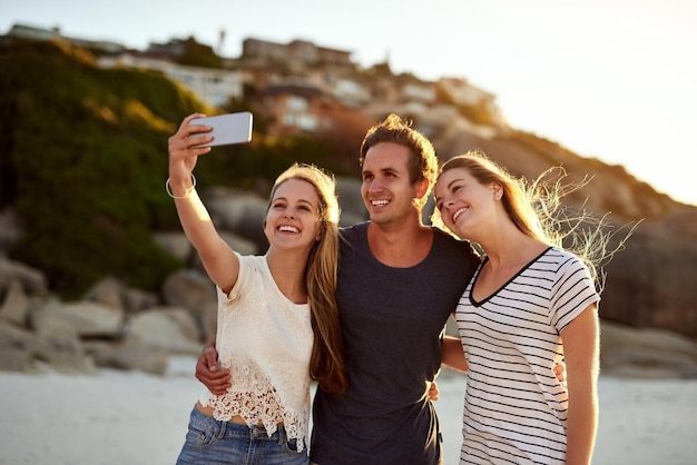 Selfies are digital memories Shot of three friends taking a selfie at the beach