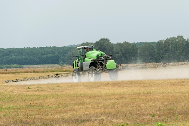 Selfpropelled sprayer works in the field on a warm sunny day\
weed control with pesticides and chemicals the tractor uses a\
sprayer to spray liquid fertilizers in the field